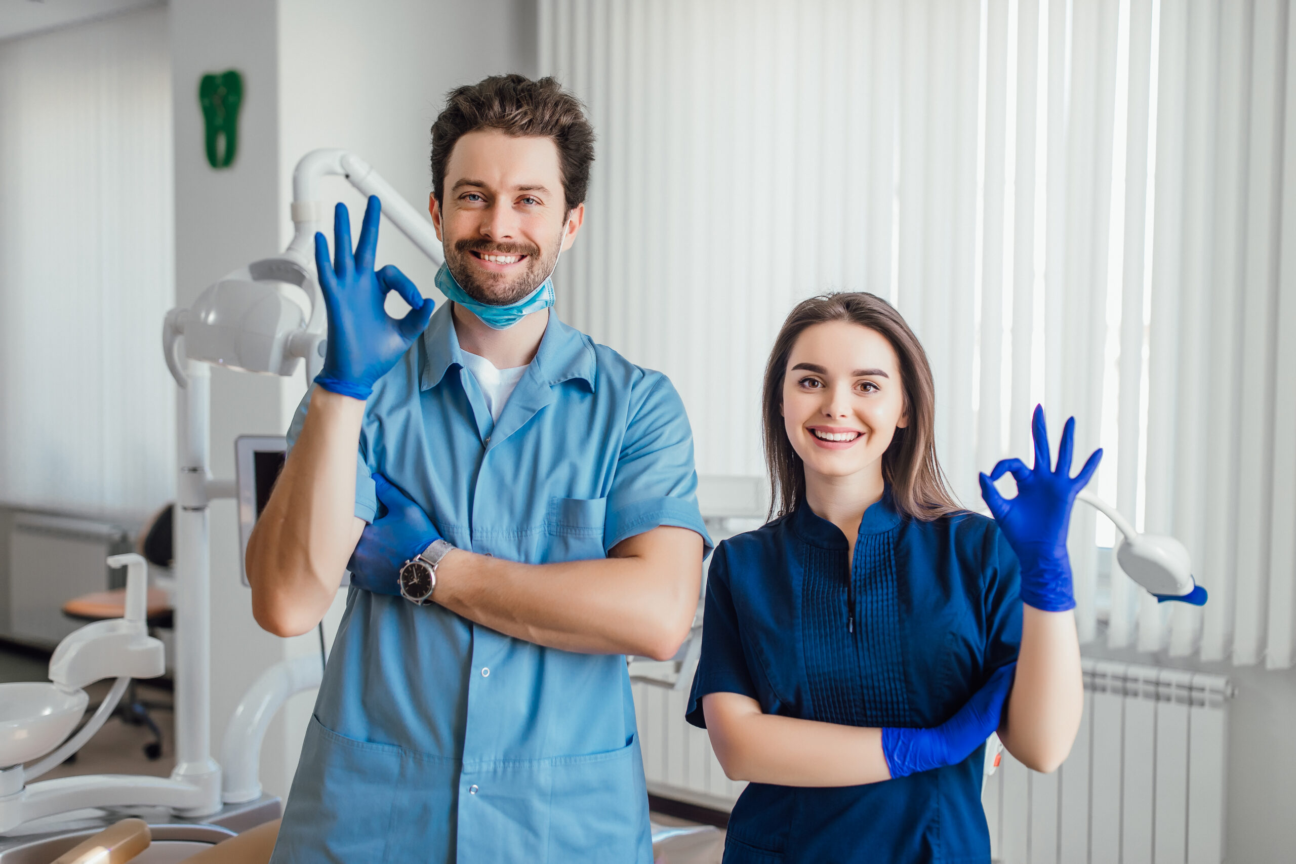 photo-smiling-dentist-standing-with-arms-crossed-with-her-colleague-showing-okay-sign-scaled.jpg